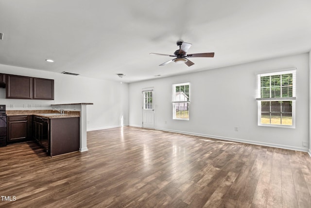 unfurnished living room featuring a sink, dark wood-style flooring, plenty of natural light, and recessed lighting