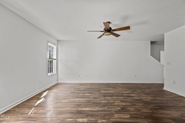 spare room featuring ceiling fan, dark wood-style flooring, and baseboards