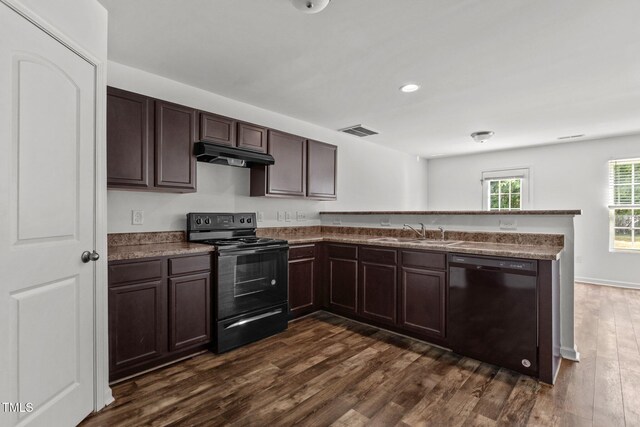 kitchen with black appliances, a sink, under cabinet range hood, a peninsula, and dark brown cabinets