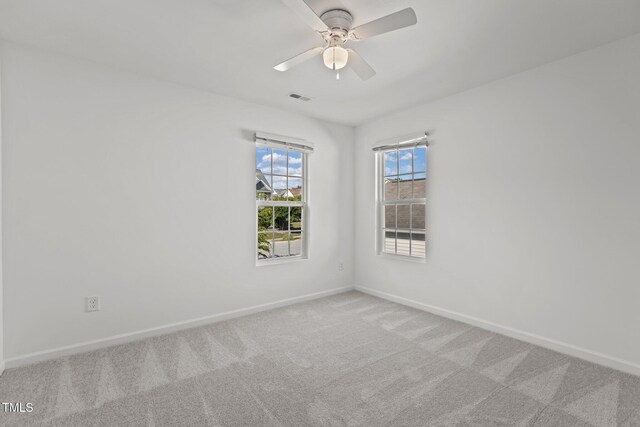 carpeted spare room featuring baseboards and a ceiling fan
