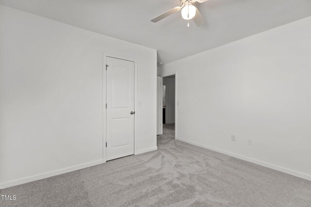 carpeted empty room with ceiling fan and baseboards
