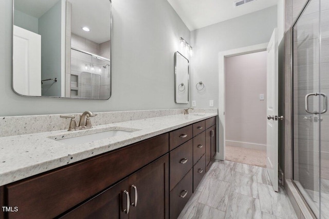 full bathroom featuring a shower stall, marble finish floors, double vanity, and baseboards