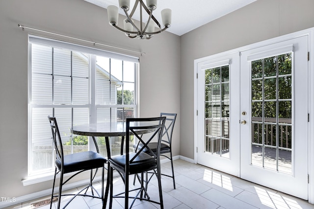 dining space with a chandelier, french doors, light tile patterned floors, and baseboards