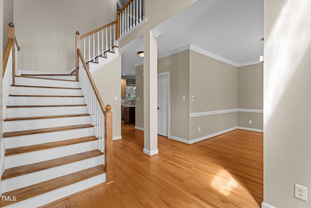 staircase featuring wood finished floors, baseboards, and ornamental molding