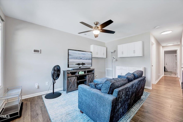 living room featuring light wood-style floors, baseboards, and a ceiling fan