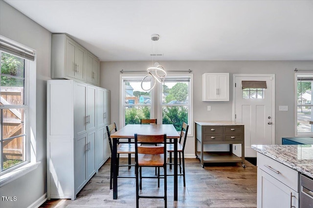 dining room with light wood-type flooring, baseboards, and a chandelier