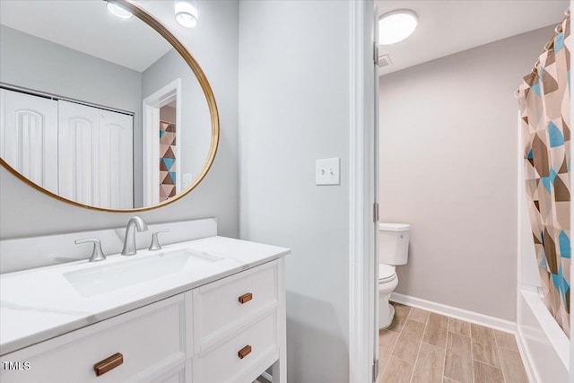 bathroom with toilet, vanity, wood finish floors, and baseboards