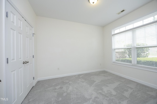 unfurnished bedroom featuring light colored carpet, baseboards, and a closet