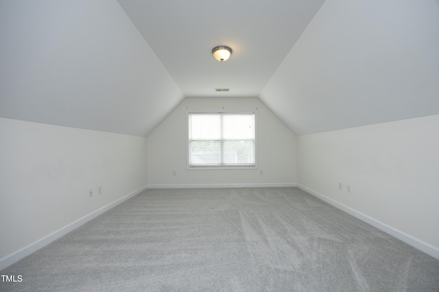 bonus room with lofted ceiling, light colored carpet, and baseboards