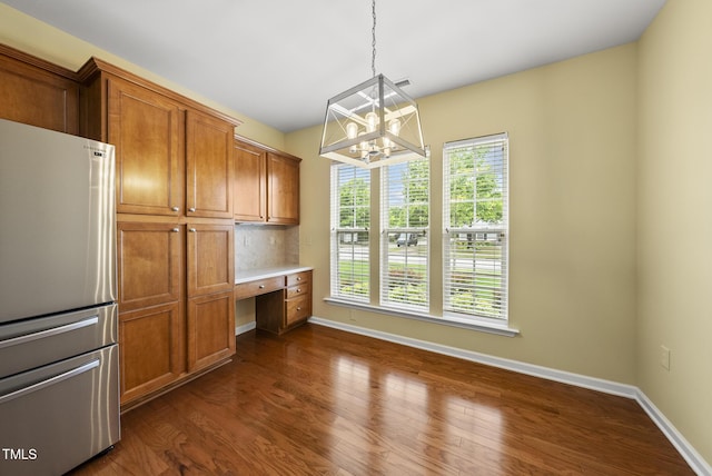kitchen featuring freestanding refrigerator, brown cabinetry, and baseboards
