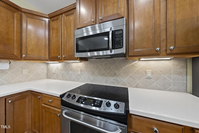 kitchen with appliances with stainless steel finishes, brown cabinetry, backsplash, and light countertops