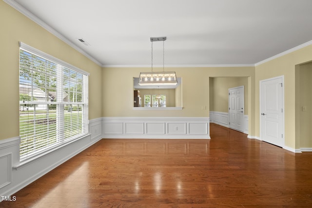 unfurnished dining area with ornamental molding, wood finished floors, and a wainscoted wall