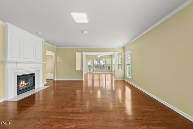 unfurnished living room featuring a premium fireplace, wood finished floors, crown molding, and baseboards