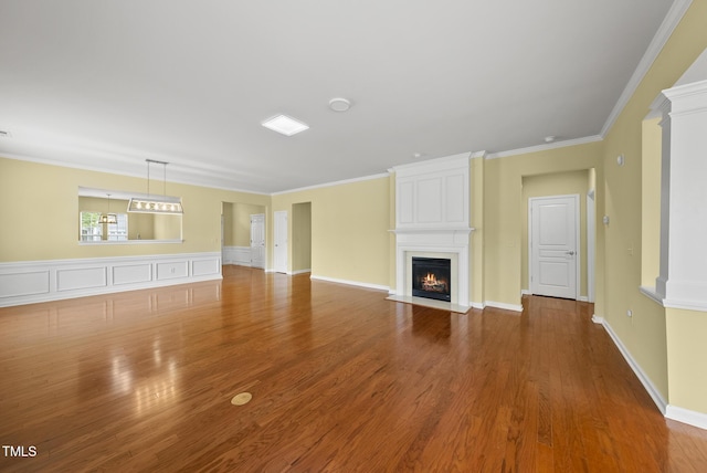 unfurnished living room featuring a fireplace, wood finished floors, and crown molding