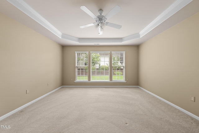 unfurnished room with a tray ceiling, ornamental molding, light carpet, baseboards, and ceiling fan