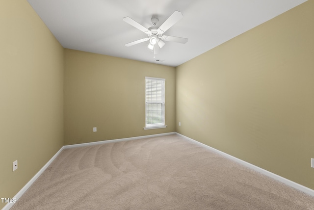 spare room with baseboards, light carpet, and ceiling fan