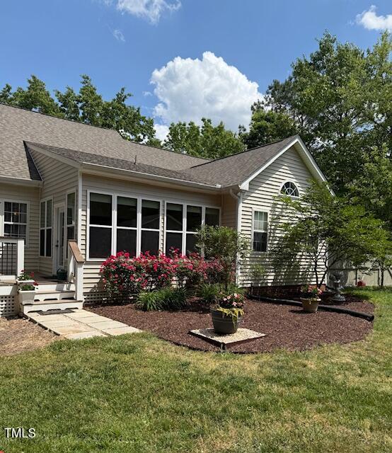 back of house featuring a lawn and a shingled roof