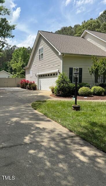 view of home's exterior featuring an attached garage, driveway, and a shingled roof