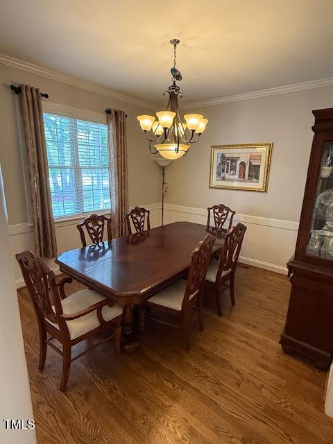 dining space featuring a chandelier, wood finished floors, and ornamental molding