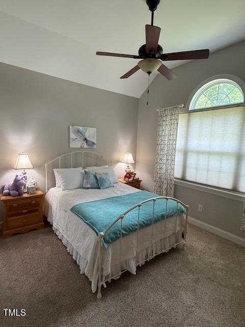 carpeted bedroom with vaulted ceiling, baseboards, and a ceiling fan
