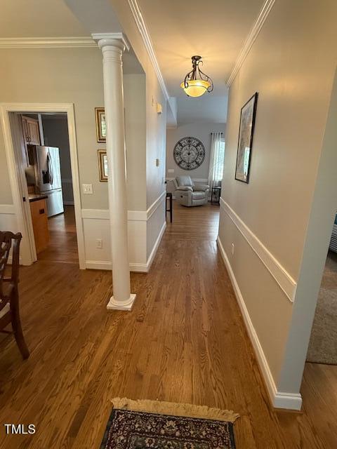 hall with crown molding, wood finished floors, decorative columns, and baseboards