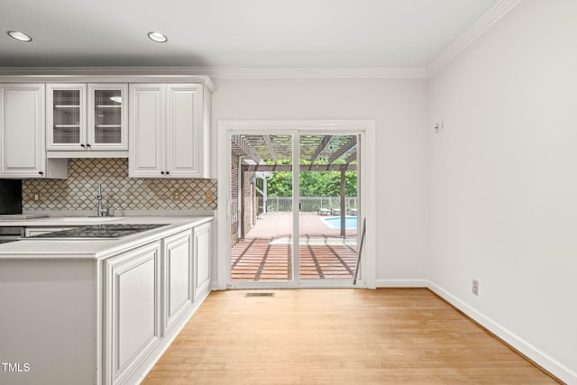 1514 Lawrence Rd, Creedmoor, NC 27522 - kitchen with light countertops, decorative backsplash, light wood-style floors, glass insert cabinets, and crown molding