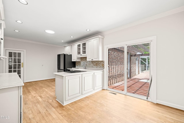 1514 Lawrence Rd, Creedmoor, NC 27522 - kitchen with freestanding refrigerator, crown molding, light countertops, white cabinetry, and a peninsula