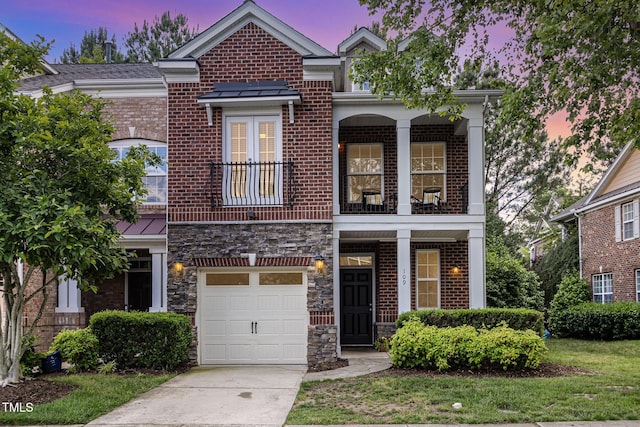 view of front of property with a balcony, an attached garage, concrete driveway, and brick siding