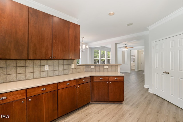 kitchen with light countertops, ornamental molding, light wood-type flooring, backsplash, and a peninsula