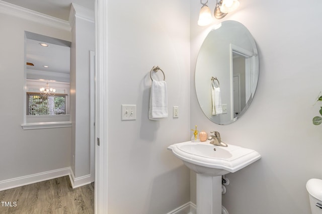 bathroom featuring a chandelier, crown molding, wood finished floors, baseboards, and toilet