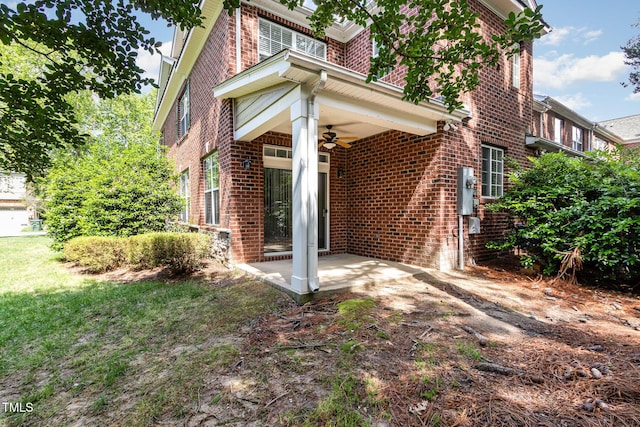 view of side of home featuring brick siding, a ceiling fan, and a patio