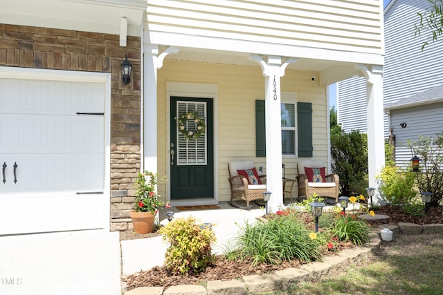 property entrance featuring a porch, stone siding, and a garage