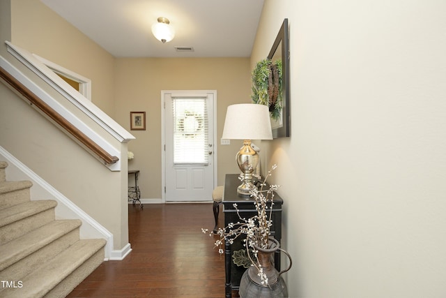foyer entrance with dark wood-type flooring, stairs, and baseboards