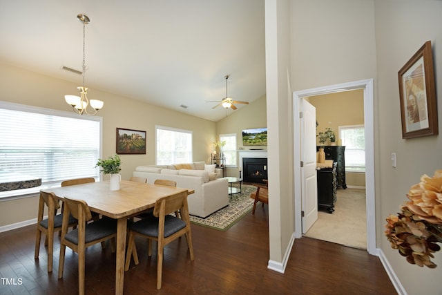 dining space featuring dark wood-style flooring, healthy amount of natural light, a lit fireplace, and high vaulted ceiling