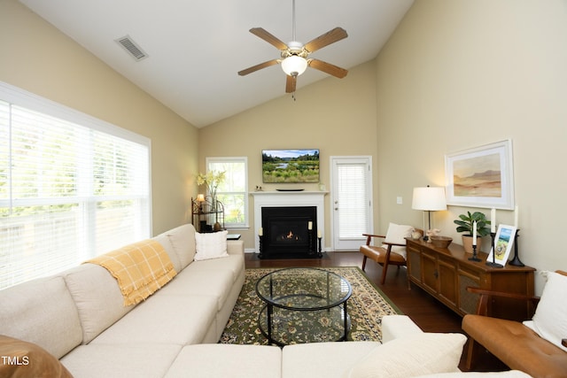 living room featuring dark wood finished floors, a ceiling fan, a fireplace with flush hearth, and high vaulted ceiling