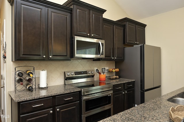 kitchen with appliances with stainless steel finishes, tasteful backsplash, dark stone countertops, and dark brown cabinetry