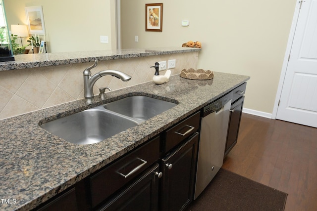 kitchen with a sink, dishwasher, dark stone countertops, dark wood-style floors, and backsplash