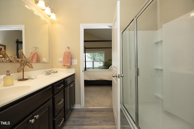 ensuite bathroom featuring wood finished floors, a shower stall, double vanity, and baseboards