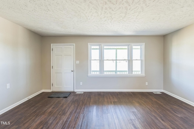 foyer entrance with dark wood-style flooring, baseboards, and a textured ceiling