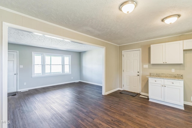 kitchen featuring a textured ceiling, dark wood-style flooring, white cabinetry, light stone counters, and crown molding