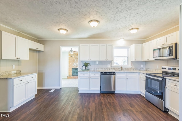 kitchen with stainless steel appliances, ornamental molding, dark wood-type flooring, a sink, and white cabinets