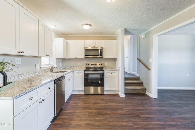 kitchen featuring appliances with stainless steel finishes, a sink, white cabinets, ornamental molding, and a textured ceiling