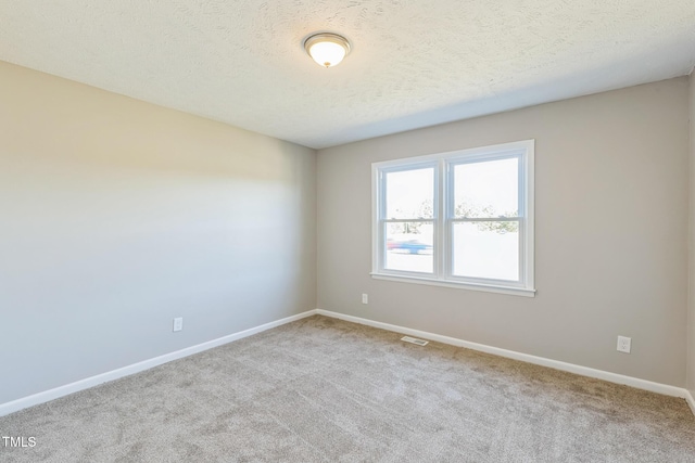 unfurnished room with carpet flooring, baseboards, and a textured ceiling