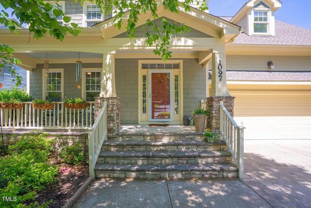 entrance to property featuring a porch, a shingled roof, driveway, and a garage