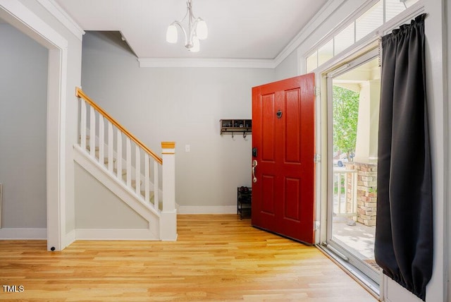 entryway featuring ornamental molding, stairs, light wood-style floors, a chandelier, and baseboards