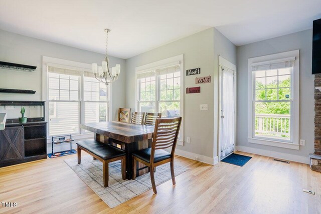dining room featuring a chandelier, light wood finished floors, and baseboards