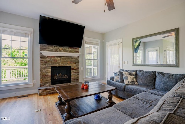 living room featuring a ceiling fan, wood finished floors, baseboards, and a fireplace
