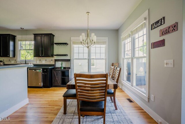 dining area with a chandelier, light wood finished floors, and baseboards