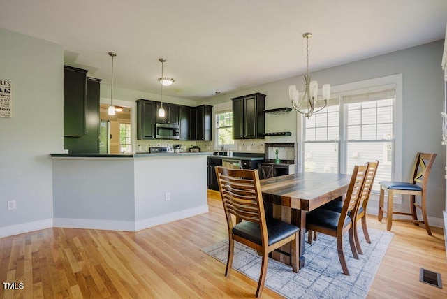 dining space featuring a chandelier, light wood-style flooring, and baseboards