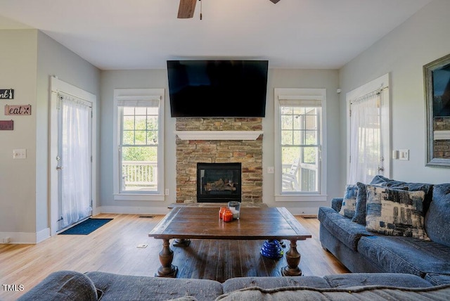 living area featuring wood finished floors, baseboards, a ceiling fan, and a fireplace